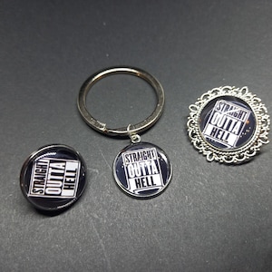 May include: A collection of accessories with the phrase "STRAIGHT OUTTA HELL" in white block letters on a black background. Includes a keychain, a button, and a decorative pin with a filigree border.