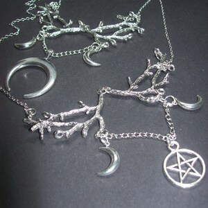 May include: Silver-toned necklaces featuring branch-like designs, crescent moons, and a pentagram pendant. The necklaces are displayed against a dark background, showcasing the intricate details of the jewelry.