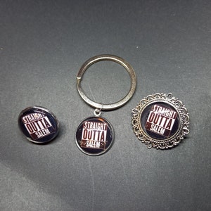 May include: Three silver-toned keychains featuring a black and white graphic that reads "Straight Outta Salem". The keychains are a pin, a charm, and a brooch.