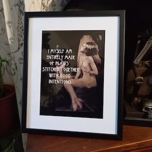 Puede incluir: Una impresi&oacute;n enmarcada en negro con un passe-partout blanco. La impresi&oacute;n presenta una imagen en blanco y negro de una mujer con una cita que dice "Yo misma estoy hecha completamente de defectos cosidos juntos con buenas intenciones".