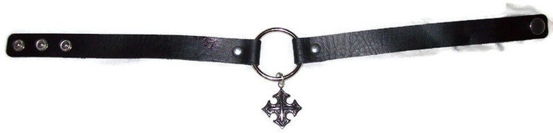 May include: Black leather choker with a silver ring and a silver cross pendant.