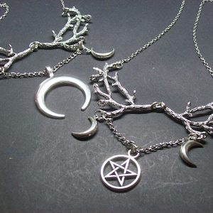 May include: Silver-toned necklaces with a celestial theme. One necklace features a crescent moon pendant, while others have small crescent moon charms and a pentagram pendant. The necklaces have a branch-like design.