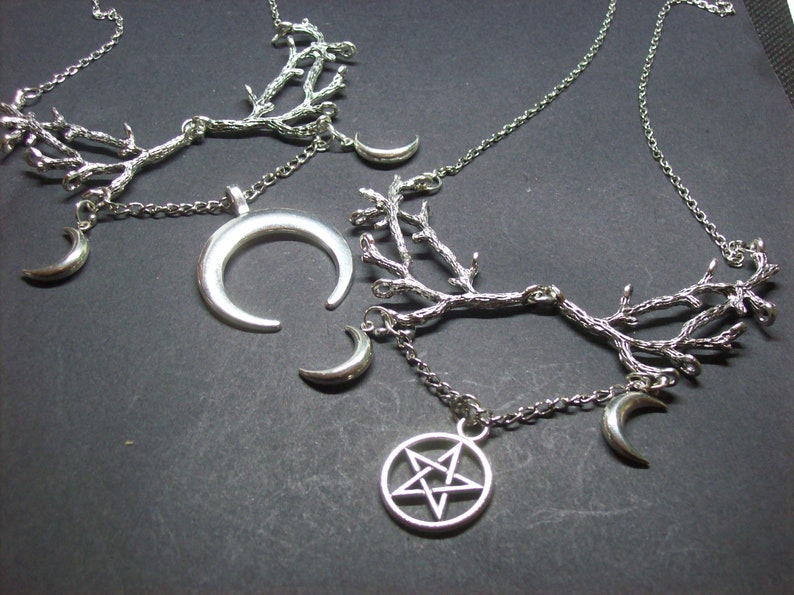 May include: Silver-toned necklaces with a celestial theme. One necklace features a crescent moon pendant, while others have small crescent moon charms and a pentagram pendant. The necklaces have a branch-like design.
