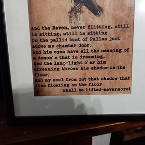 May include: Framed print featuring a poem with a raven illustration. The text, in a vintage typewriter font, includes the lines "And the Raven, never flitting...Shall be lifted-nevermore!" The print is in a black frame.