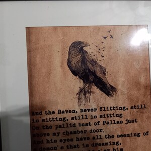 May include: Framed artwork featuring a detailed illustration of a raven perched on a branch, with a flock of birds flying away. The artwork is set against a textured, sepia-toned background with text from a poem.