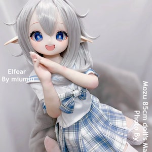 May include: A white haired doll with blue eyes wearing a white and blue plaid skirt and a white sailor collar shirt with a blue bow. The doll is 85cm tall and is called Elfear by miumu.