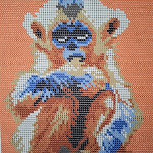 Puede incluir: Un patrón de punto de cruz azul y blanco de un mono con un sombrero azul y blanco y una bufanda azul. El mono lleva un abrigo marrón y naranja.