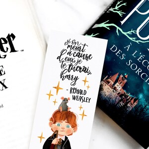 K&ouml;nnte beinhalten: Ein wei&szlig;es Lesezeichen mit einer Illustration von Harry Potter und einem Zitat auf Franz&ouml;sisch, das lautet "Si on meurt &agrave; cause d'eux je te tuerai, Harry - Ronald Weasley". Die Illustration zeigt einen Cartoon von Harry Potter mit einer Ratte auf dem Kopf und goldenen Sternen im Hintergrund.