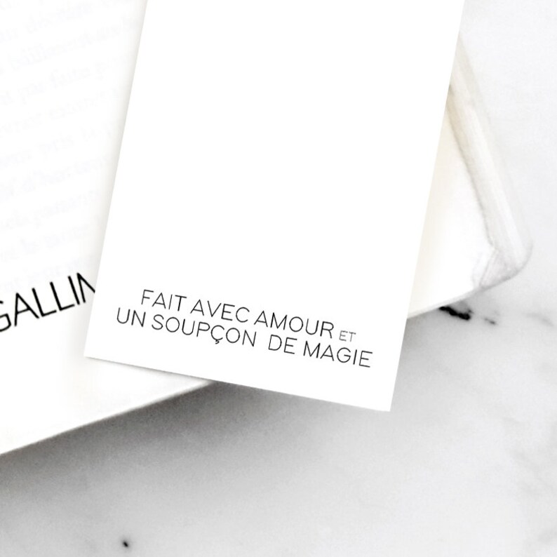 K&ouml;nnte beinhalten: Eine wei&szlig;e Karte mit schwarzem Text, der "FAIT AVEC AMOUR ET UN SOUP&Ccedil;ON DE MAGIE" lautet.