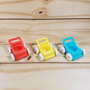 May include: Three vintage toy push carts in red, yellow, and blue. Each cart has a white cup and four white wheels.