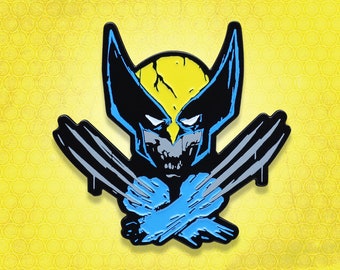 May include: A black and blue enamel pin featuring a cartoon depiction of Wolverine with his claws extended. The character's face is yellow and has a menacing expression.