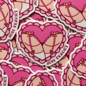 May include: A set of pink and white heart-shaped stickers with a pink and white lingerie design and the text "Just Peachy".