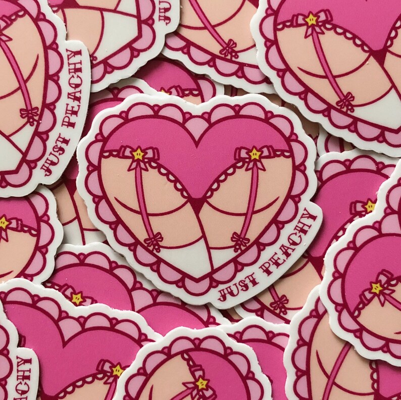 May include: A set of pink and white heart-shaped stickers with a pink and white lingerie design and the text "Just Peachy".