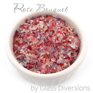 May include: A small white bowl filled with red, pink, and clear glass pieces. The glass pieces are small and irregular in shape. The bowl is labeled "Rose Bouquet by Glass Diversions".