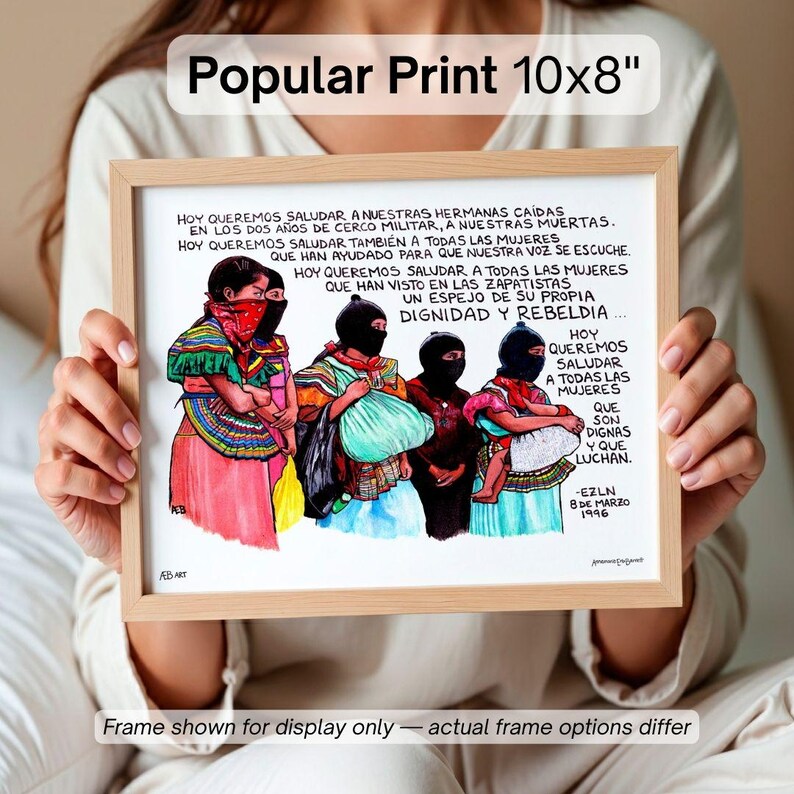 May include: A framed print, labeled "Popular Print 10x8", features a colorful illustration of women in traditional attire, some wearing black masks. The artwork includes Spanish text and is set in a light-colored wooden frame. The print measures 10 inches by 8 inches.