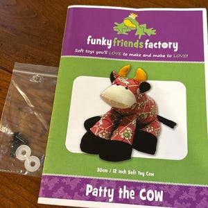May include: A soft toy cow sewing pattern kit. The pattern is for a 12-inch cow named Patty. The kit includes a pattern booklet with the Funky Friends Factory logo, a clear bag with parts, and a finished cow image.