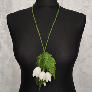 Pu&ograve; includere: Una collana di fiori bianchi in feltro con foglie verdi. La collana &egrave; realizzata in feltro ed &egrave; un gioiello delicato e femminile.