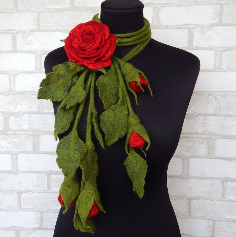 May include: A red felt rose with green felt leaves and stems, forming a long scarf or necklace.