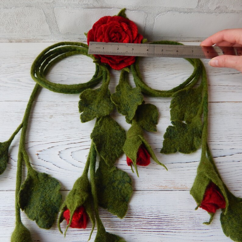 May include: A felt garland with red roses and green leaves. The garland is approximately 10 inches long.