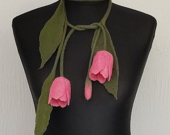 May include: A long green felt necklace with three pink felt tulips attached. The necklace is tied in a knot at the back of the neck.