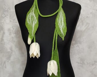 May include: A long green felt necklace with white felt flowers. The necklace is made of felt and is a unique and stylish accessory.