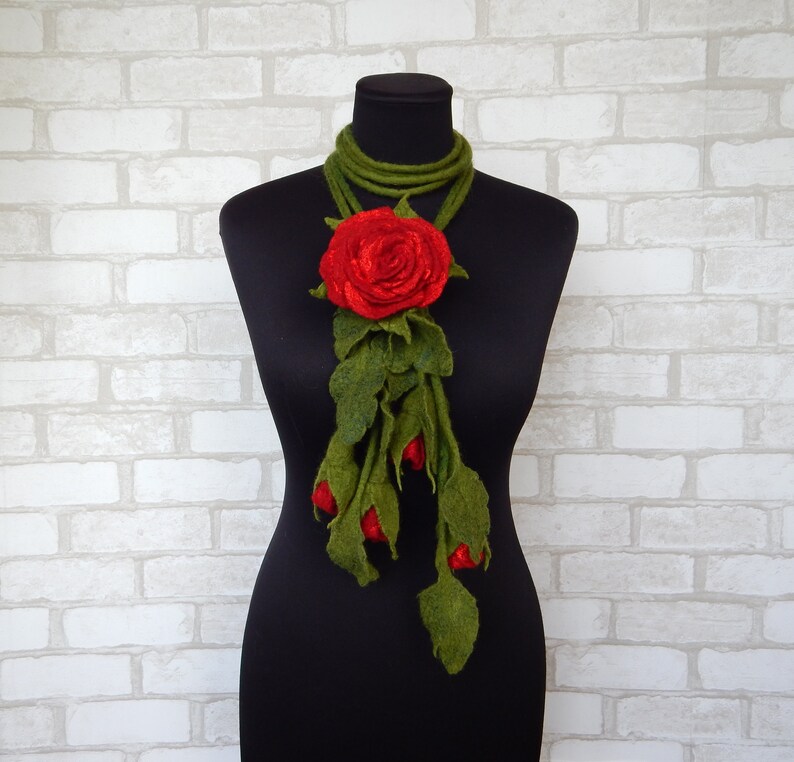 May include: A red felt rose with green felt leaves and stems, arranged as a long necklace.