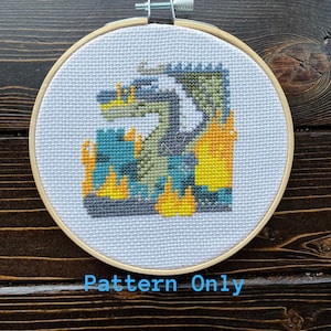 Puede incluir: Un patrón de punto de cruz de un dragón con un esquema de color turquesa, gris, verde y amarillo. El patrón está enmarcado en un aro de madera y el texto "Pattern Only" está impreso debajo del aro.