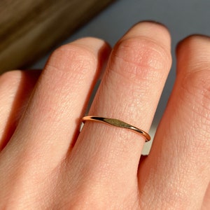 May include: A thin gold band ring worn on a finger.