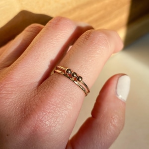 May include: A gold ring with three small gold beads on the band.