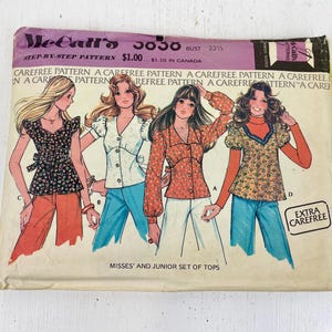 May include: A vintage McCall's 5636 sewing pattern for tops, featuring illustrations of four different styles. The envelope is cream-coloured with purple and green text. The text includes 'Carefree Pattern' and 'Misses' and Junior Set of Tops'.