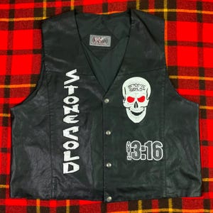 Peut inclure: Un gilet noir avec un logo Stone Cold vertical blanc, un graphique de crâne blanc aux yeux rouges et le texte Austin 3:16 en blanc. Le gilet présente un col en V, une fermeture à boutons sur le devant et une étiquette WWE au col intérieur.