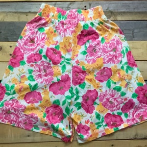 Può includere: Shorts bianchi con stampa floreale rosa e gialla. I pantaloncini hanno una fascia elastica in vita.