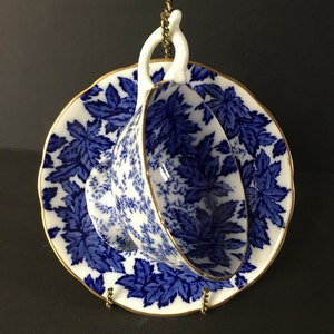 May include: A blue and white teacup and saucer with a floral pattern. The saucer has a gold rim.