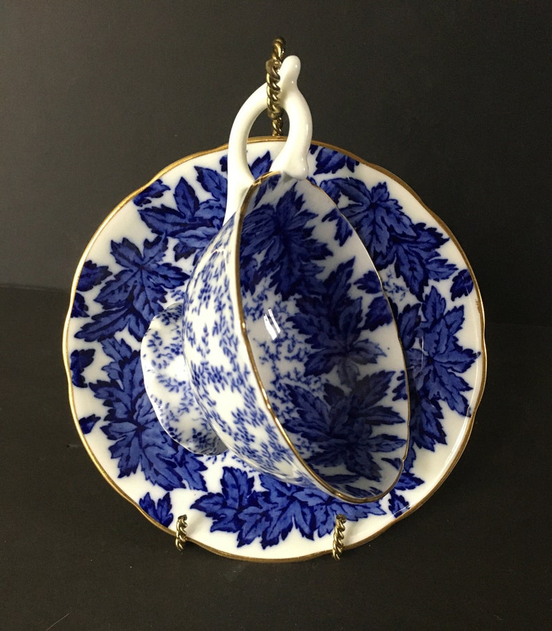 May include: A blue and white teacup and saucer with a floral pattern. The saucer has a gold rim.
