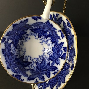 May include: A blue and white teacup and saucer with a gold rim and a floral pattern. The cup and saucer are stacked on top of each other.