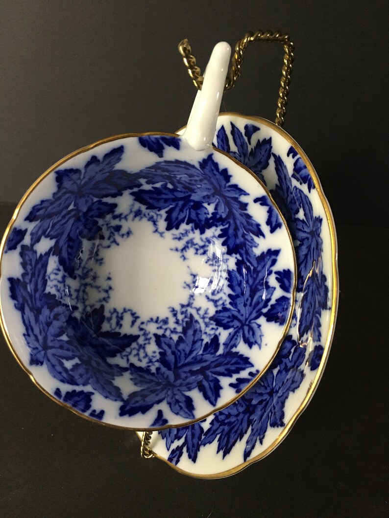 May include: A blue and white teacup and saucer with a gold rim and a floral pattern. The cup and saucer are stacked on top of each other.