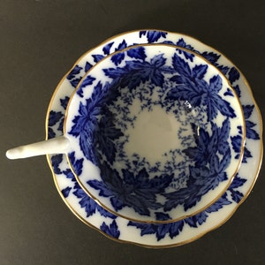 May include: A vintage teacup and saucer set with a blue and white floral pattern. The cup and saucer have a gold trim.