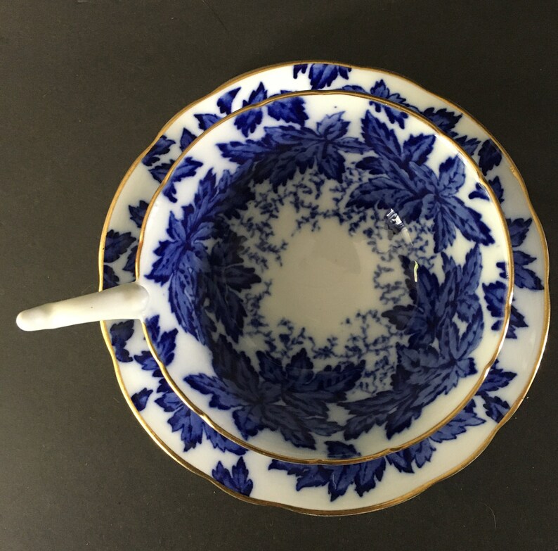 May include: A vintage teacup and saucer set with a blue and white floral pattern. The cup and saucer have a gold trim.