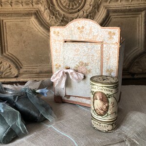 May include: A vintage, white, paper-covered box with a pink ribbon and a round, white and gold tin with the text "Nell Gwynne" and "Yardley, New Bond St, London".