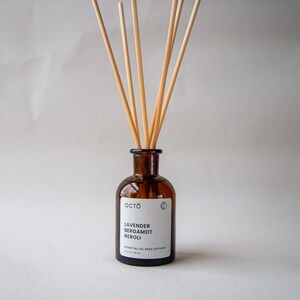 May include: A brown glass bottle with a white label that reads "OCTO Lavender Bergamot Neroli Essential Oil Reed Diffuser 4.2 fl oz / 125 ml". The bottle has wooden sticks sticking out of the top.