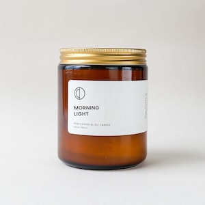 May include: A brown glass jar candle with a gold lid. The label reads "MORNING LIGHT" and "PURE ESSENTIAL OIL CANDLE". The candle contains 250 ml of product.
