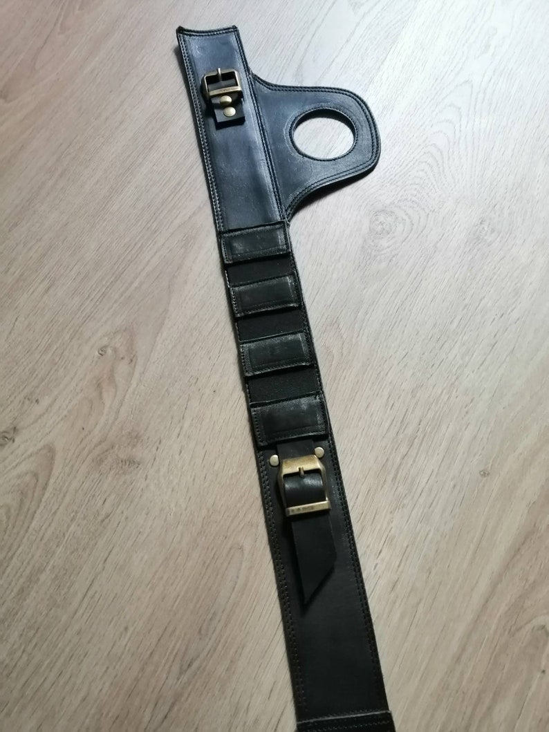 Puede incluir: Cintur&oacute;n de cuero negro con hebilla y un lazo. El cintur&oacute;n tiene una serie de ranuras verticales en la parte delantera.