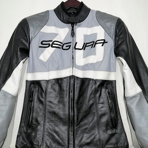 May include: Black, white, and gray leather motorcycle jacket with the word "SEGURA" and the number "70" on the front.