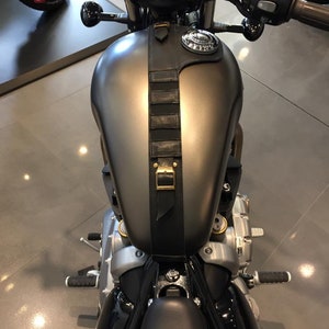 Puede incluir: Una motocicleta negra con un tanque de gasolina gris y una correa de cuero negra con una hebilla de lat&oacute;n. La motocicleta tiene un asiento negro y un manillar negro.