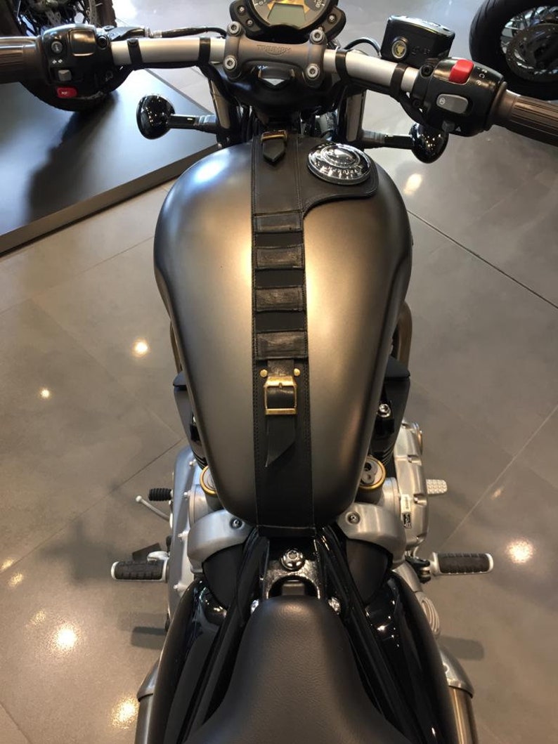 Puede incluir: Una motocicleta negra con un tanque de gasolina gris y una correa de cuero negra con una hebilla de lat&oacute;n. La motocicleta tiene un asiento negro y un manillar negro.