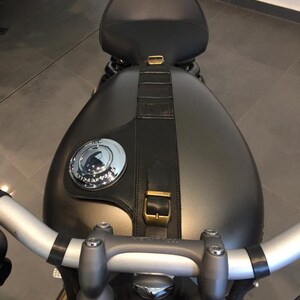 Puede incluir: Una motocicleta negra con un tanque de gasolina gris y un asiento de cuero negro. La motocicleta tiene un manillar plateado y una correa de cuero negro con una hebilla de lat&oacute;n.