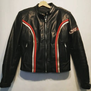 Może przedstawiać: Czarna skórzana kurtka motocyklowa z czerwonymi i białymi paskami wyścigowymi i logo "Helston's" na kołnierzu.