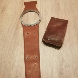 May include: A brown leather belt with a silver metal ring and a matching brown leather pouch.