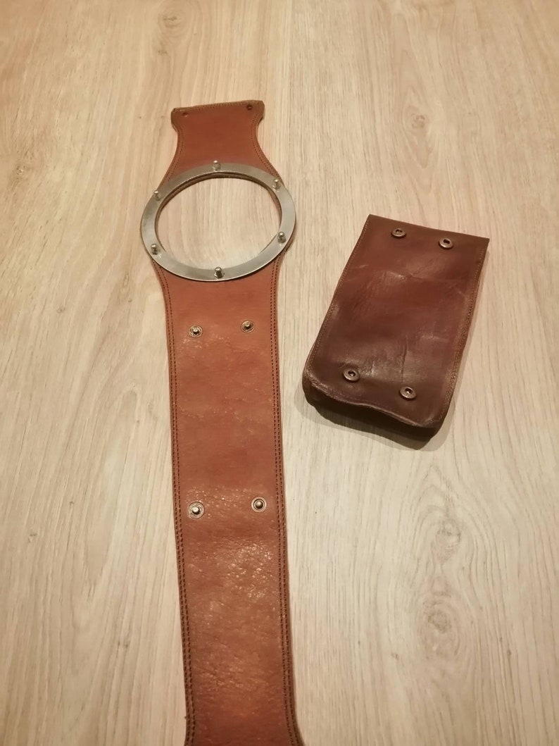 May include: A brown leather belt with a silver metal ring and a matching brown leather pouch.