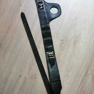 Puede incluir: Cintur&oacute;n de cuero negro con hebilla y un lazo en el lateral. El cintur&oacute;n tiene una correa que se puede ajustar para adaptarse a diferentes tama&ntilde;os.